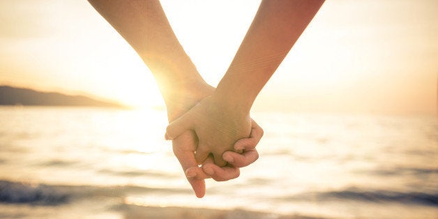 Couple of lovers holding their hands at a beautiful sunset over the ocean - Newlywed couple on a romantic vacation