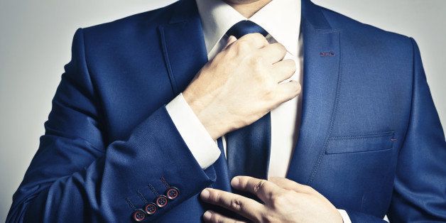 Businessman in blue suit adjusting his tie