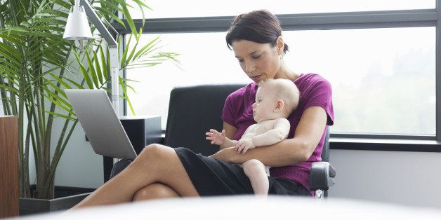 Woman holding baby using laptop