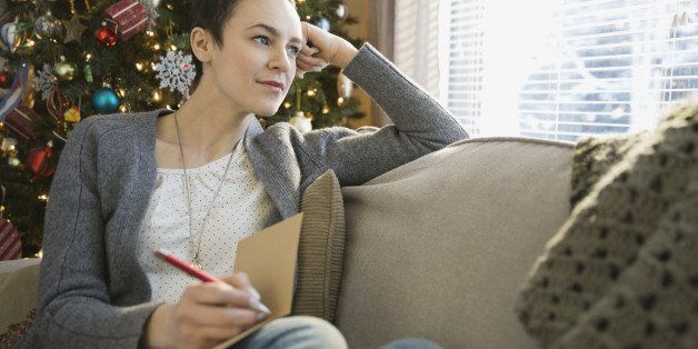 Thoughtful woman writing in Christmas cards at home