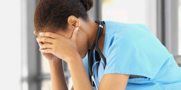 Close-up side view of a young surgeon frowning with her hands holding her head