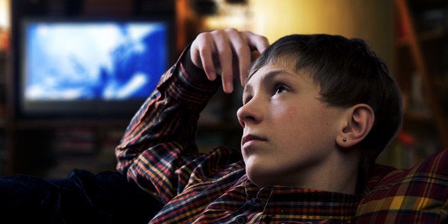 Teenage boy lies at pillows and drreaming on the background of evening home interior