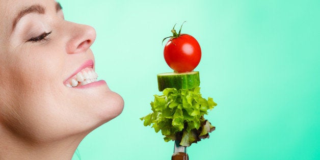 Healthy eating and diet concept. Closeup happy young woman holding vegetables on green blue background. Studio shot.