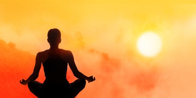 women meditating on high mountain in sunset background