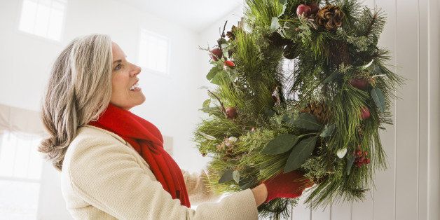 Caucasian woman hanging Christmas wreath on door