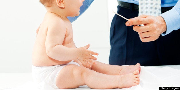 Male doctor, pediatrician checking little baby girl throat at the pediatrician's office