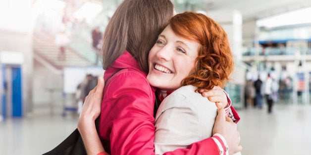 women greeting, embracing, at arrival hall.