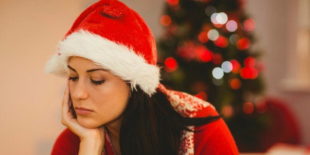 Festive brunette feeling sad at christmas at home in the living room