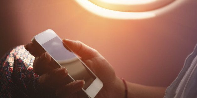 Woman using smartphone in airplane during flight