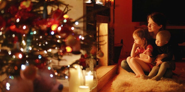 Young mother and her daughters by a fireplace on Christmas