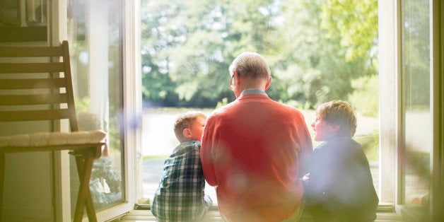 Grandfather and grandsons sitting in doorway