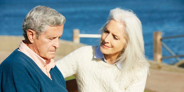 Senior Woman Comforting Depressed Husband Sitting On Bench