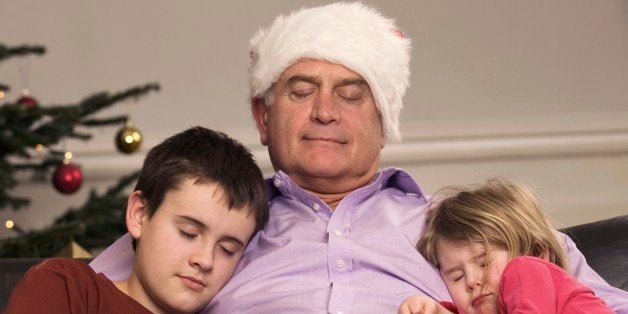 Grandfather and grandchildren asleep on sofa on Christmas