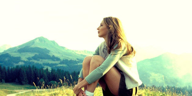 Woman sitting on mountainside