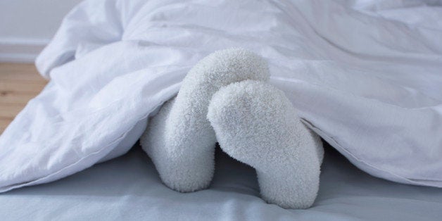 detail of woman lying in bed showing feet in woollen socks