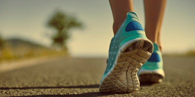 Closeup of athlete female feet in running shoes jogging on the road early in the morning. Healthy lifestyle.