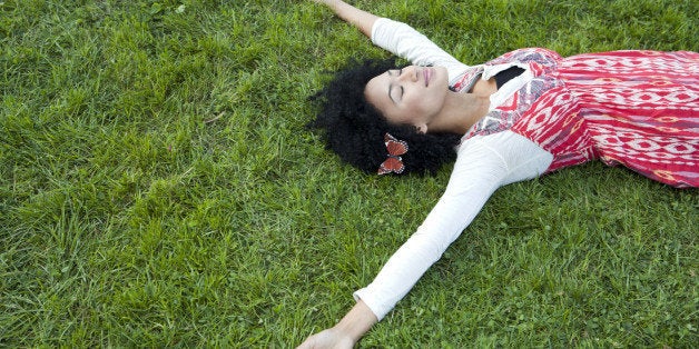 Woman with eyes closed lying on grass