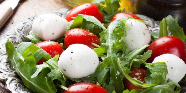 Fresh italian salad with mozzarella cheese, tomato and rucola on vintage old metal plate. Healthy food. Selective focus.