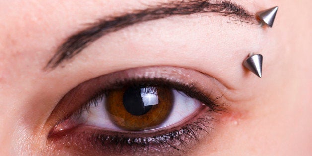 Brown female eye with an eyebrow piercing