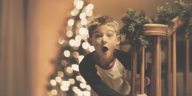 little boy coming down stairs with a surprised expression, Christmas tree in the background.