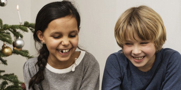 Girl and boy in front of Xmas tree laughing