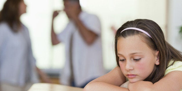 Sad looking girl with her fighting parents behind her