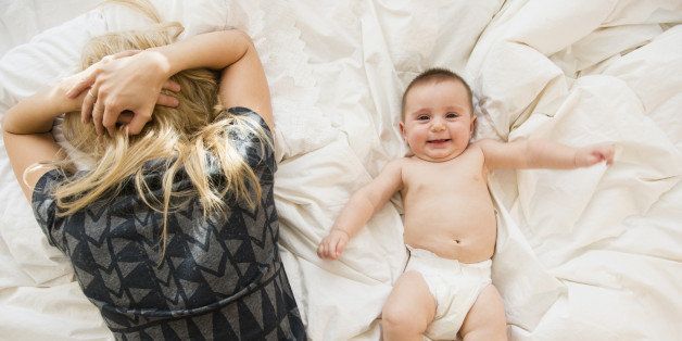 Mother exhausted in bed next to baby