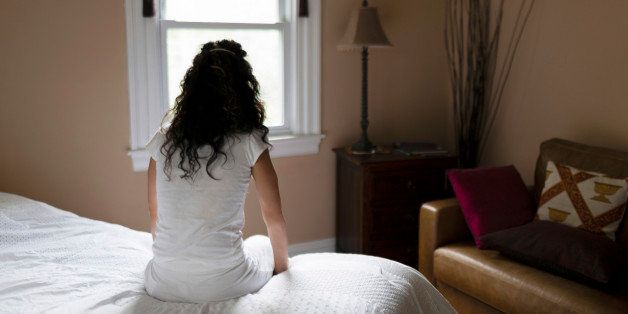 Woman sitting on edge of bed