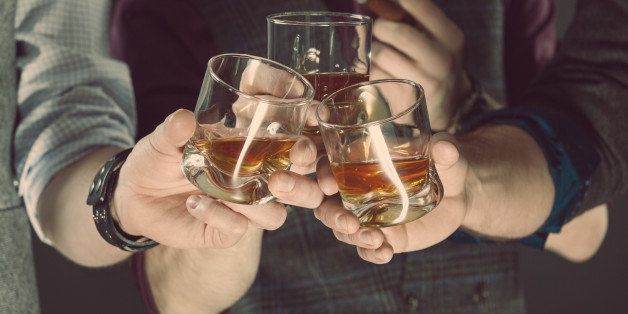 Three men drinking whiskey. Close up of glasses and hands. Dark tone. 