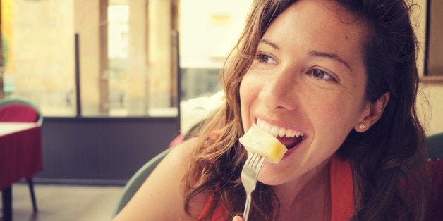 Natural portrait of pretty young woman eating seme fruit in an outdoor restaurant.