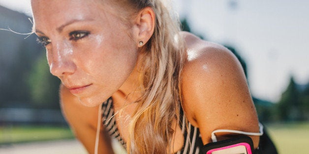 Sweaty, blond haired woman having a rest after hard workout on a sports field.