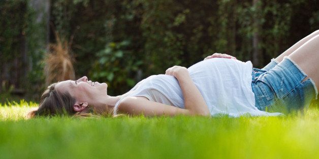 Young pregnant woman lying on grass