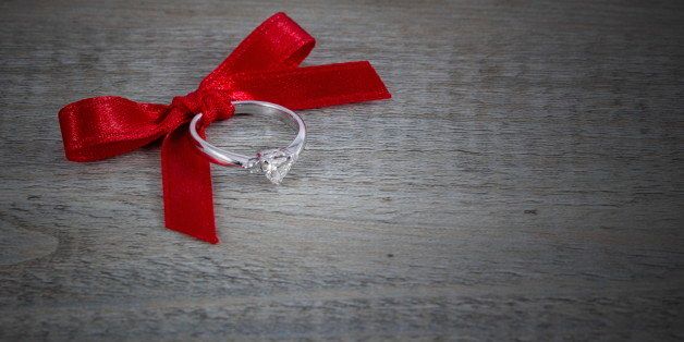 Red bow with diamond ring on wooden background