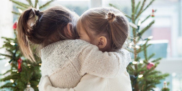 Girls hugging in front of Christmas trees