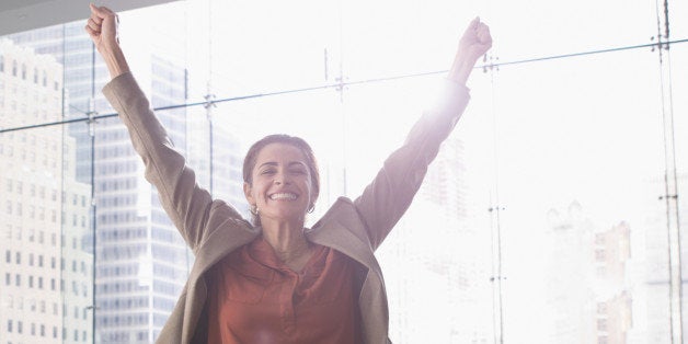 Hispanic businesswoman cheering in office