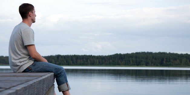 A young man sitting alone by the water