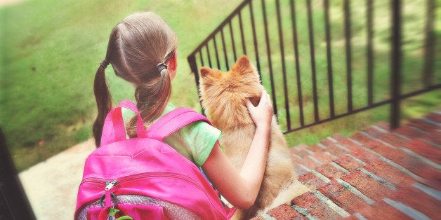 young girl with pink backpack sitting on the steps with her Pomeranian dog in the morning waiting on the school bus