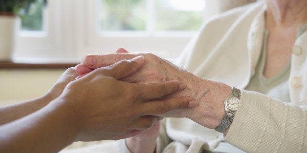 Close up of older woman and caretaker holding hands