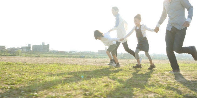 Parents with two kids holding hands and running