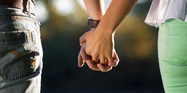 A Young Couple Holding Hands In The Sunset