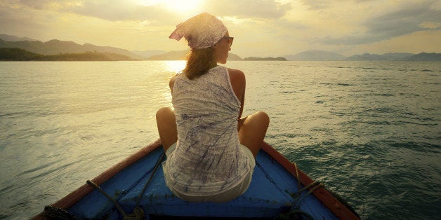 Woman traveling by boat at sunset among the islands.