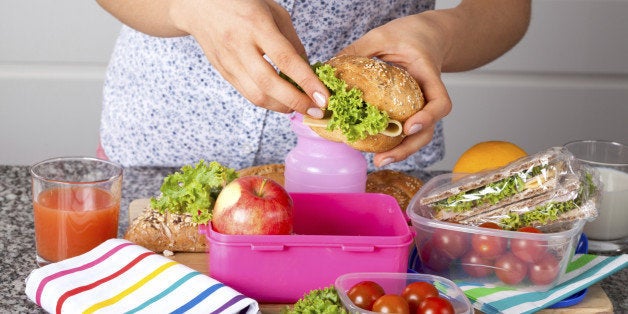 Woman preparing delicious sandwich with cheese and green salad