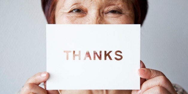 an old woman holding a card with a message, THANKS, written on it.