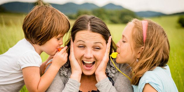 Children blowing whistles to mother's ears- outdoor in nature