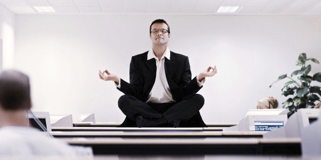 Businessman meditating on office desk