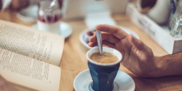 Young man drinking coffee in a cafe. Close-up.