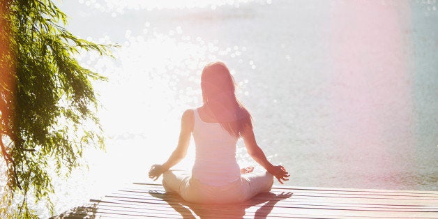 Woman practicing yoga on pier