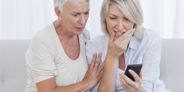 Woman reading bad news through text message with her friend comforting her
