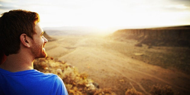 Smiling man looking out over desert canyon at sunset