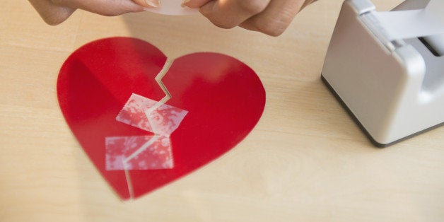 Mixed race woman taking broken paper heart